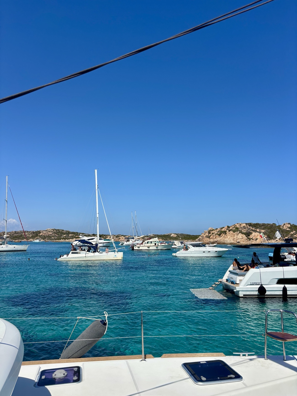 Boats gathered in the turquoise water off the Sardinian coast