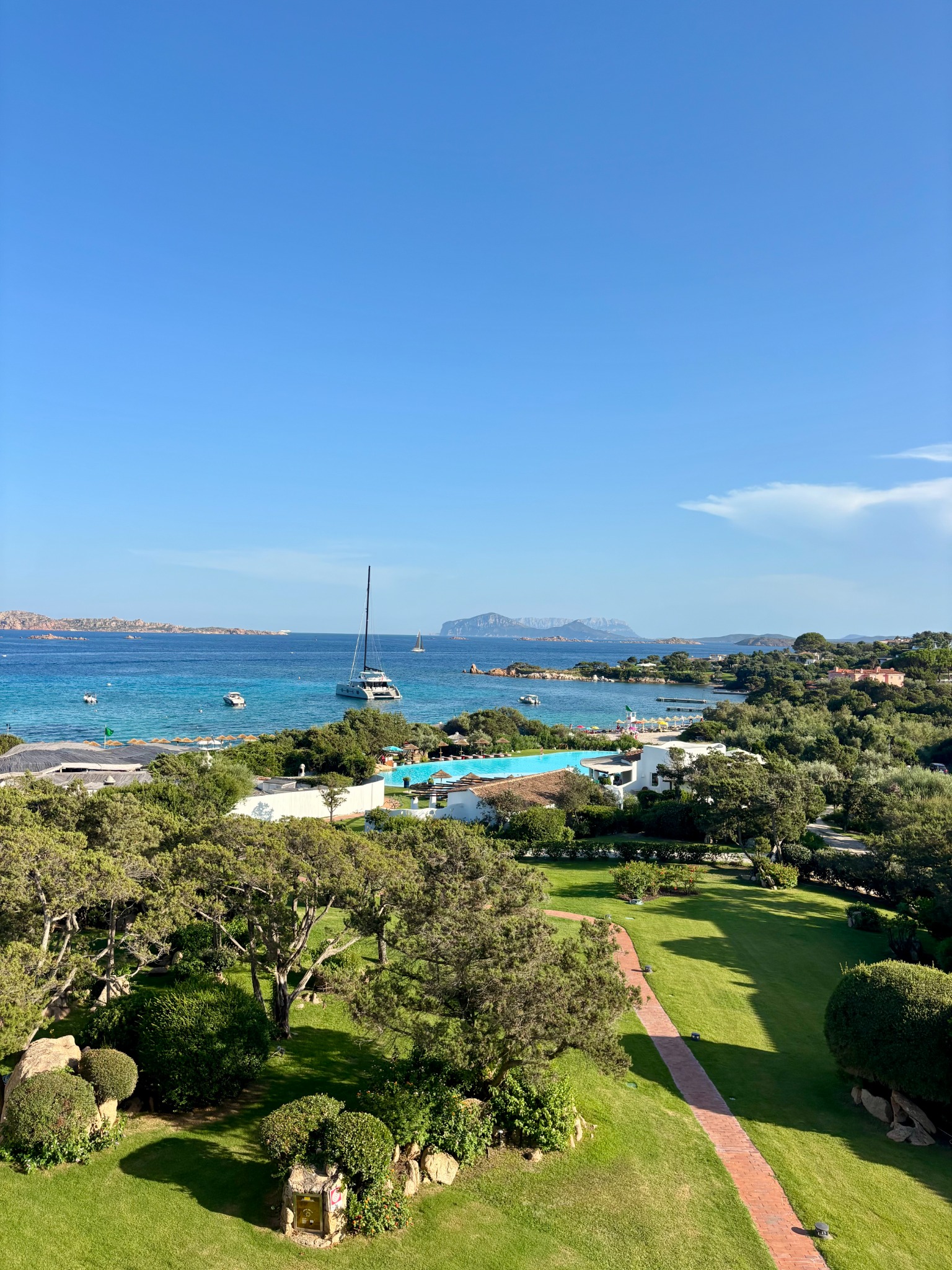 View across Sardinian gardens and coastline to blue water and distant islands
